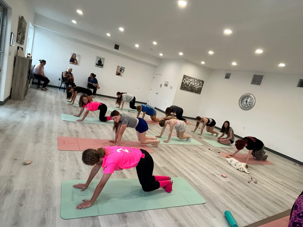 Guests practicing pilates with a puppy in the studio at Pawsitively Pilates