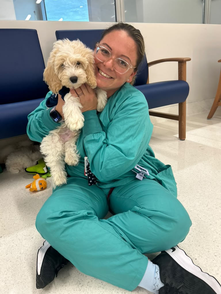 Healthcare worker hugging a puppy during a hospital visit