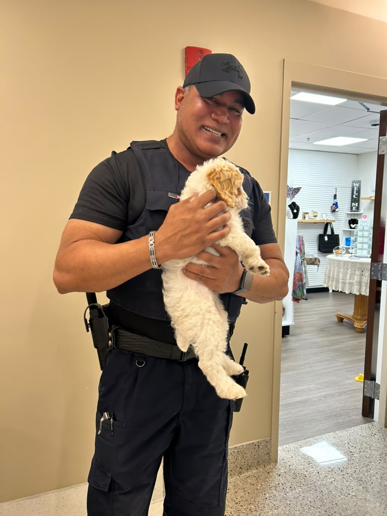 Hospital security staff member holding a puppy during a visit