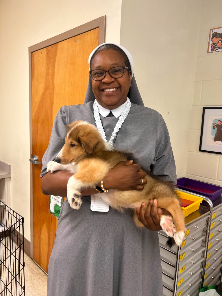 School staff member holding a puppy during a classroom visit