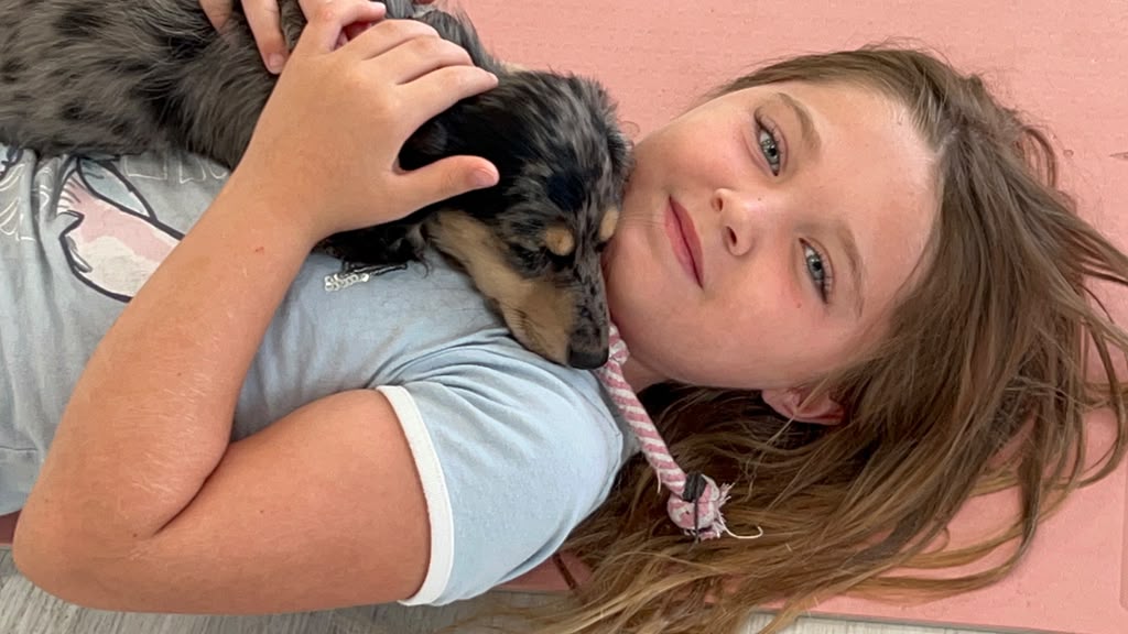Guest lying on a yoga mat cuddling a puppy in the studio