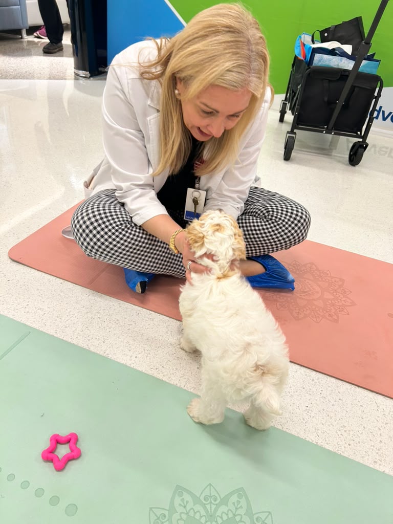 Guest sitting on a mat with a puppy at an off-site event