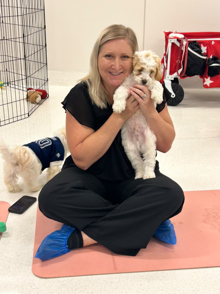 Guest sitting on a mat with a puppy at an off-site event